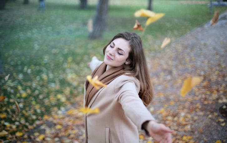 Frau tanzt durchs Herbstlaub