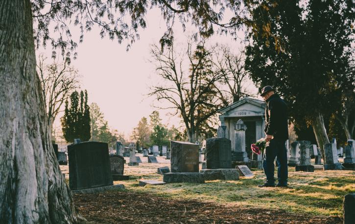 Ein Mann bringt Blumen auf den Friedhof