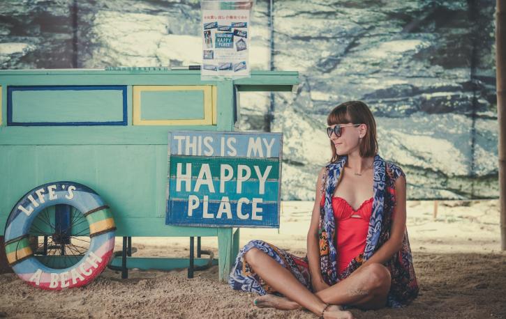 Eine Frau sitzt neben einem Schild mit der Aufschrift "This is my happy place"
