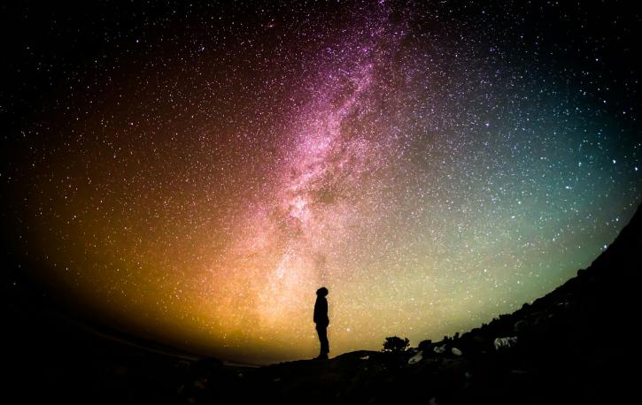 Die Silhouette einer Person vor einem Sternenhimmel bei Nacht.