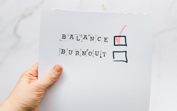 Eine Hand hält ein Papier, auf dem BALANCE und BURNOUT steht und BALANCE abgehakt wurde, BURNOUT nicht