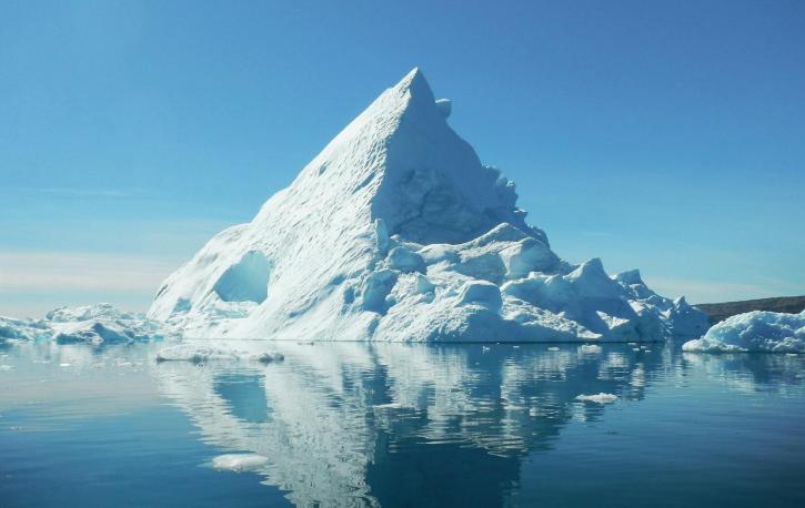 Ein spitzer Eisberg im Meer umgeben von kleineren Eisschollen