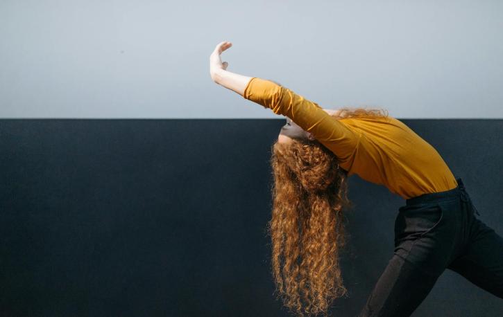 Eine Frau wird im Profil gezeigt, sie neigt den Oberkörper nachhinten, wie in einer Ballettpose.