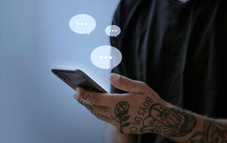 Ein Mann hält ein Smartphone in der Hand, drei Sprechblasen sind darüber eingefügt.
