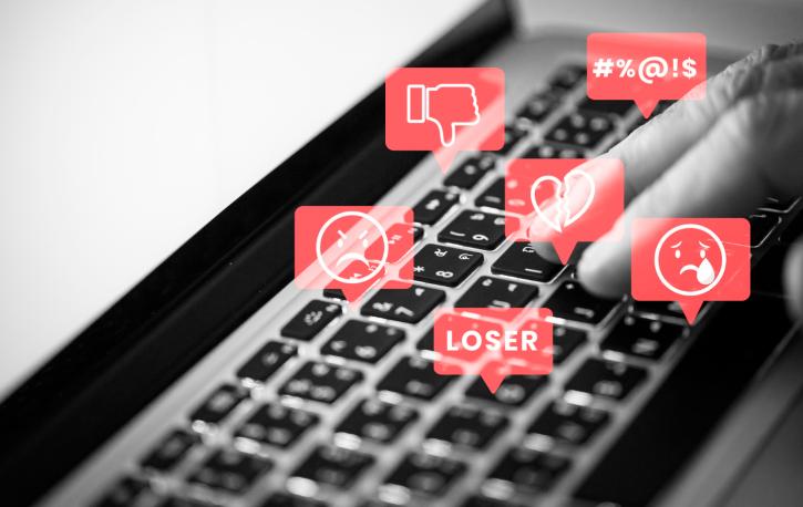Eine Tastatur mit Hatespeech-Symbolen in Sprechblasen darüber