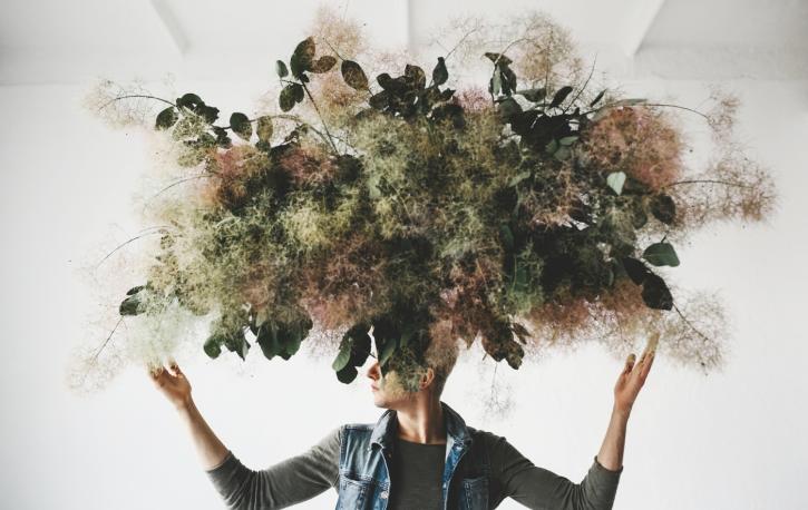 Eine Person, über und auf deren Gesicht ein Pflanzenwirrwarr schwebt
