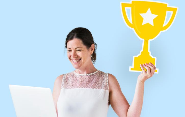 Eine Frau hält einen Papp-Pokal hoch.