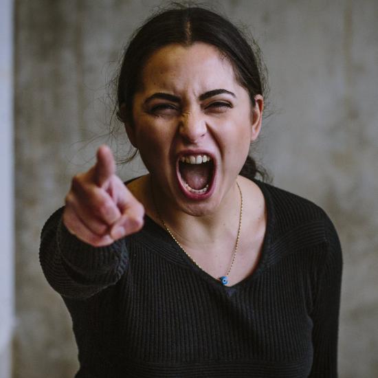 Wütende Frau zeigt mit Zeigefinger in Richtung Kamera