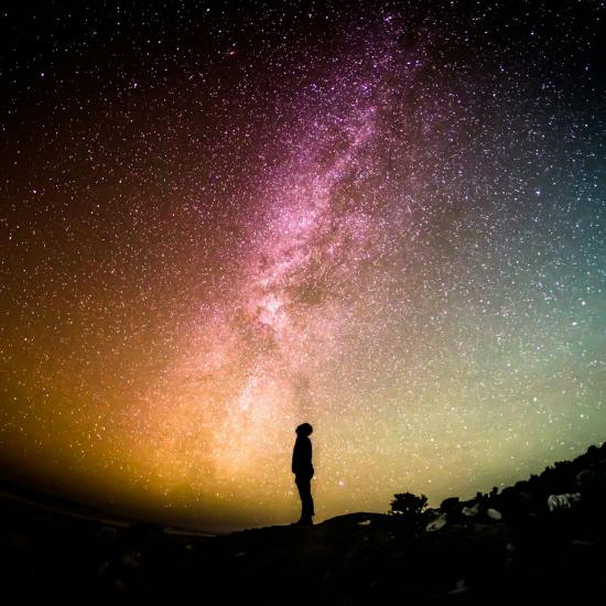 Die Silhouette einer Person vor einem Sternenhimmel bei Nacht.