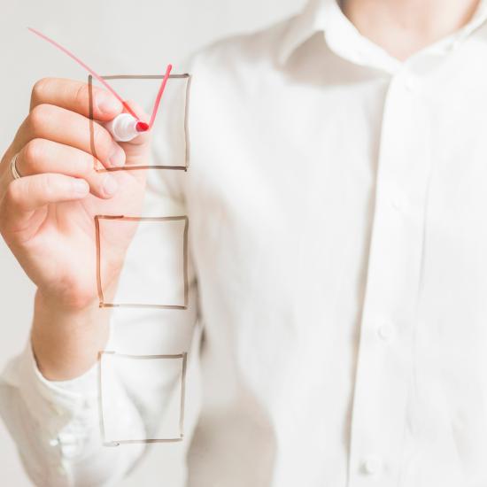 Man sieht den Oberkörper einer Person, die ein Häkchen in eines von drei Kästchen zeichnet