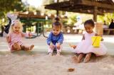 Drei kleine Kinder sitzen im Sandkasten und spielen