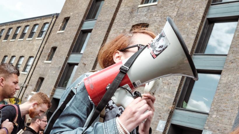Demonstration: Im Vordergrund läuft eine Frau mit einem Megafon in der Hand.