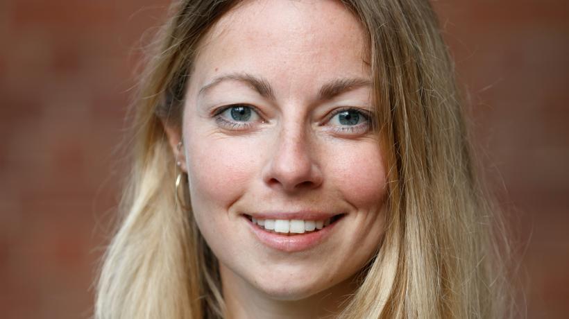 Foto von Marie Bette. zu sehen ist eine Frau mit langen blonden Haaren und mintgrünem Pullover vor einer Steinwand.