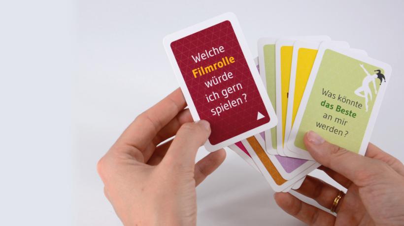 Man sieht zwei Hände, die mehrere Therapiekarten in der Hand halten.