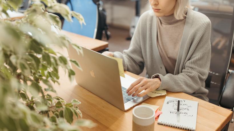Frau sitzt vor dem Laptop und tippt auf der Tastatur.