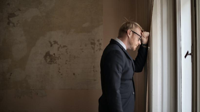 Mann lehnt niedergeschlagen den Kopf an die Wand