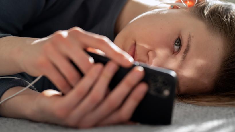 Eine Frau liegt auf der Seite und schaut auf ihr Smartphone
