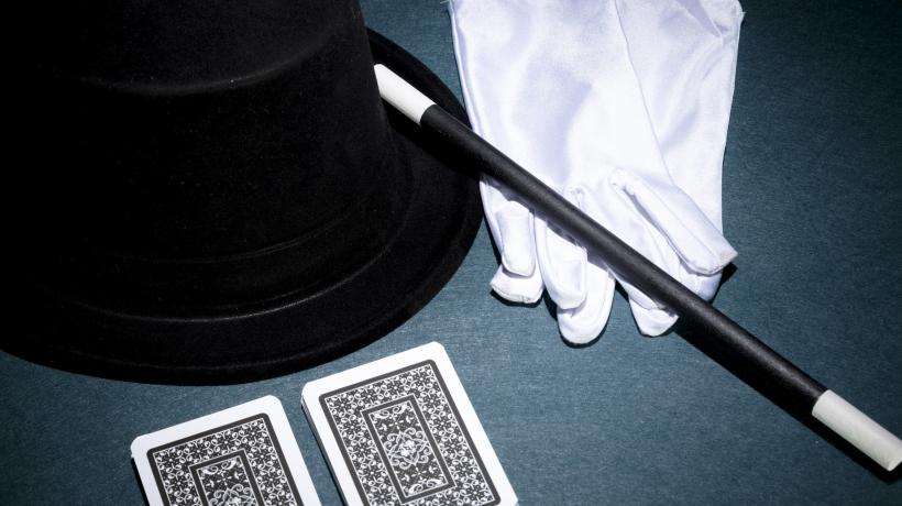 Zwei Spielkarten, ein Zauberstab, ein schwarzer Hut und weiße Handschuhe