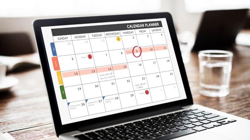 Ein aufgeklappter Laptop, auf dessen Display ein Kalender zu sehen ist.