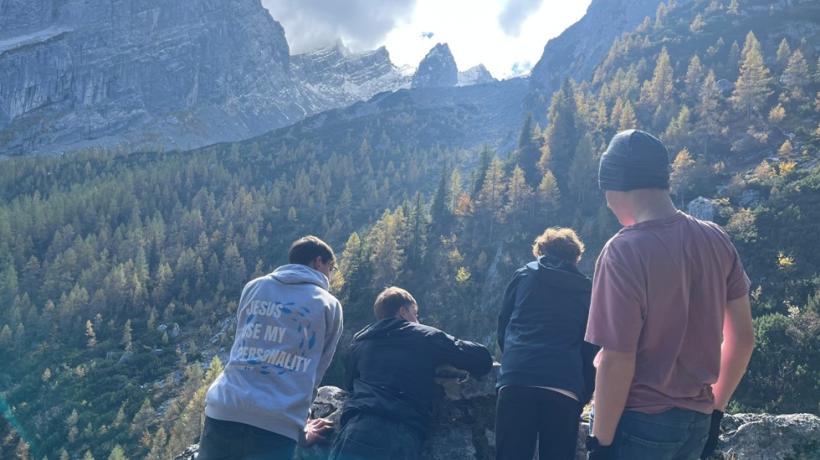 Vier Jugendliche von hinten, die durch eine alpine Landschaft laufen.