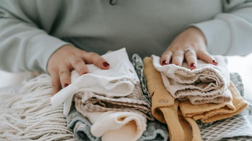 Eine Frau legt ihre Hände auf einen Stapel gewaschener Babykleidung