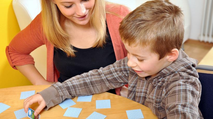 Frau und Junge spielen zusammen "Memory".