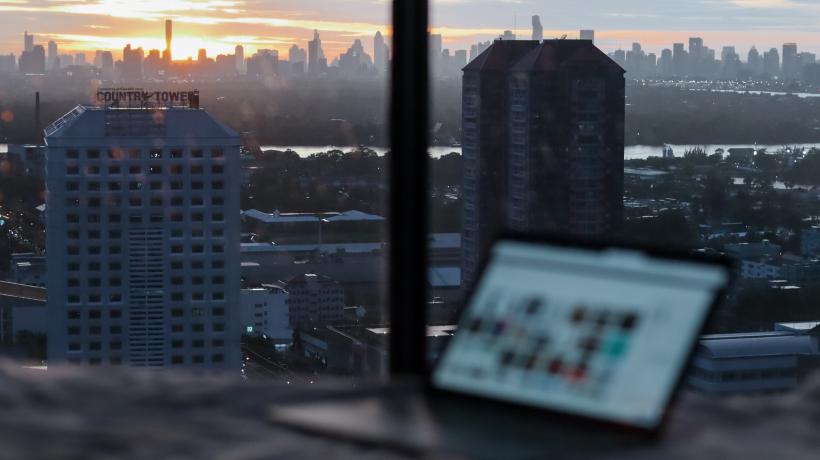 Laptop steht vor Fenster, aus dem man die Skyline von Bangkok.