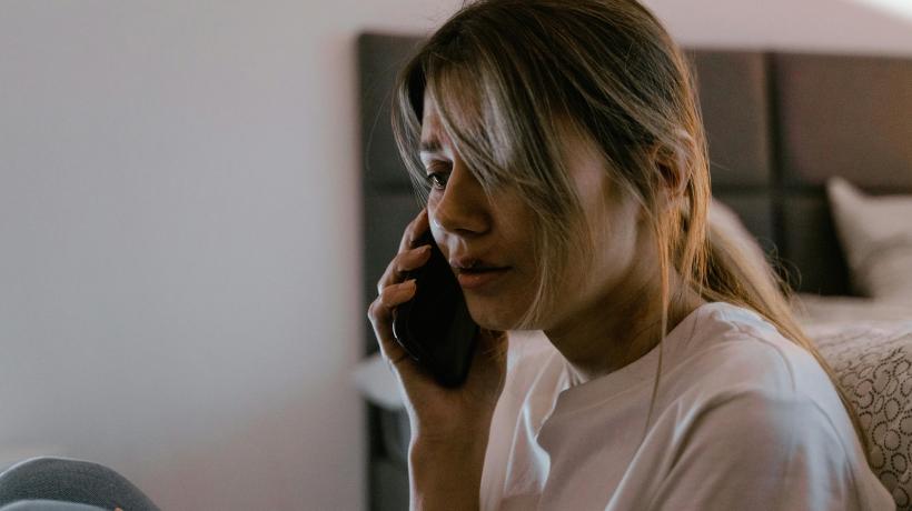 Eine verzweifelt schauende Frau hält ein Telefon am Ohr.