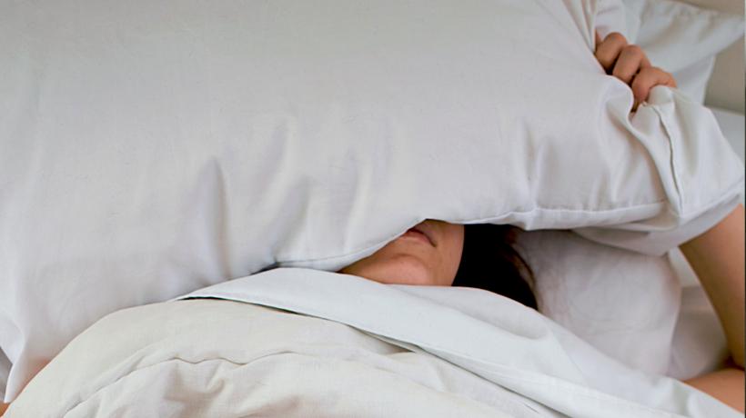 Person versteckt sich unter einem Kissen.
