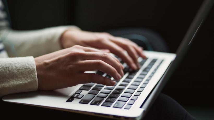 Zwei Hände tippen auf Laptop Keyboard.