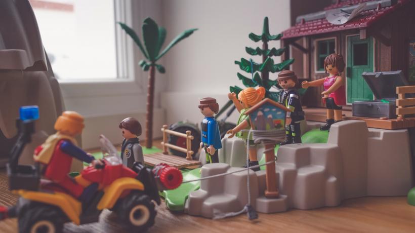 Playmobildorf mit Traktor, Figuren, Bäumen und Häusern auf dem Fußboden.