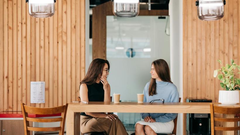 Zwei Frauen sitzen in einem Café und unterhalten sich.