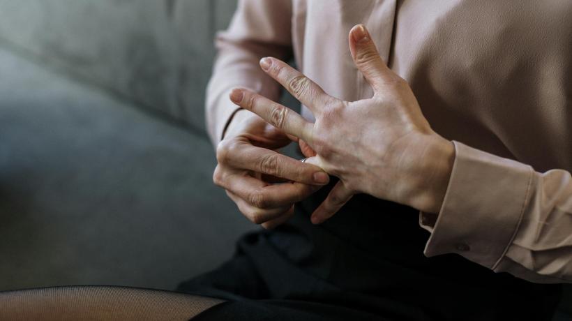 Nahaufnahme der Hände einer Frau, die sich den Ring vom Finger zieht.