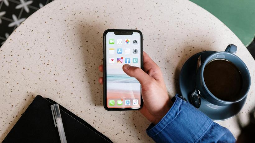 Eine Hand hält ein Smartphone, man sieht das Menü.
