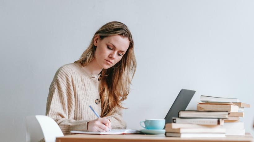 Frau lernt mit Büchern und Laptop an einem Tisch