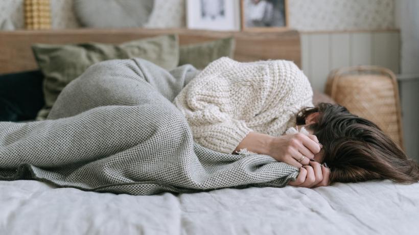 Frau kauert sich aufs Bett