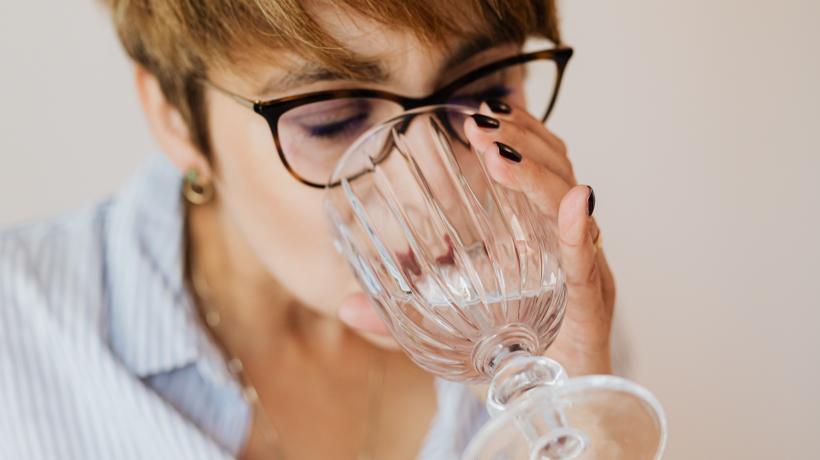 Frau greift nach Wasserglas und trinkt.