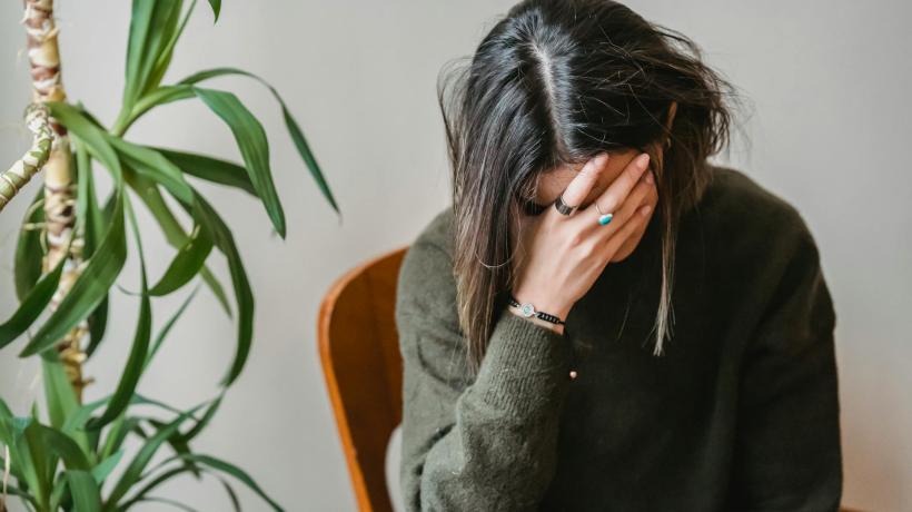 Eine Frau sitzt auf einem Stuhl und stützt den Kopf in die Hand.