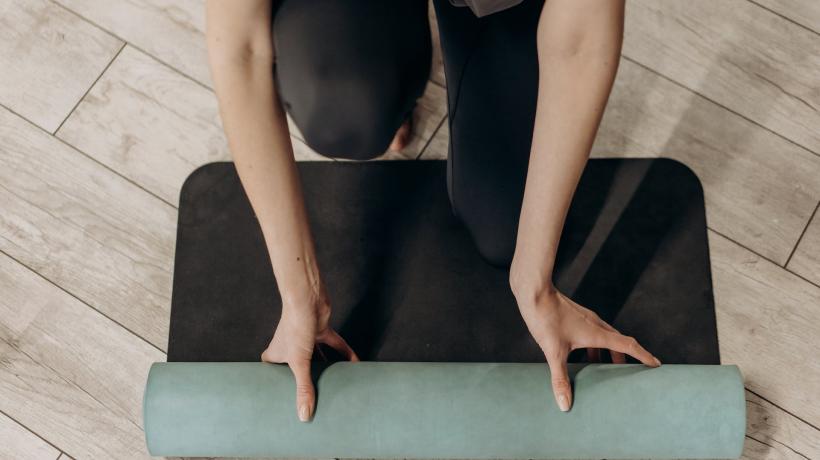 Bild einer Person von oben, die ihre Yogamatte ausrollt.