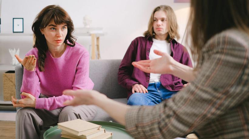 Drei Frauen sitzen zusammen auf einer Coach und diskutieren.
