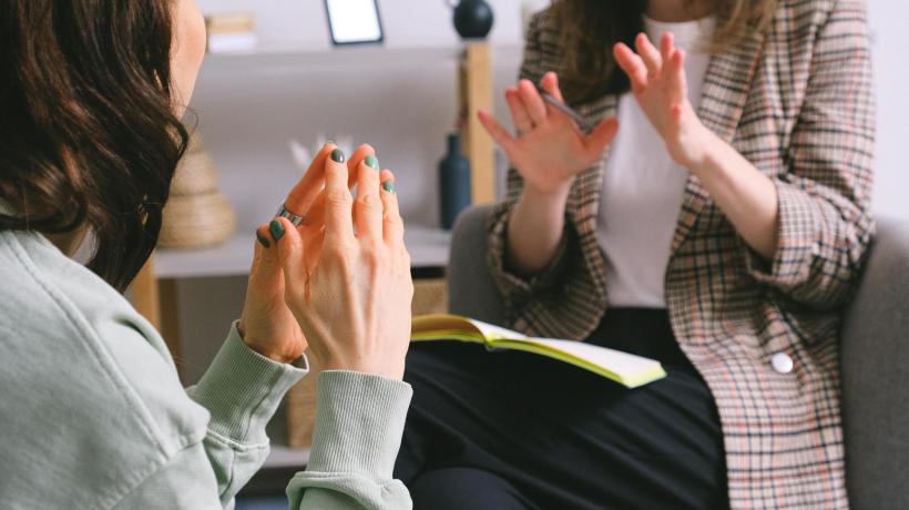 Nahaufnahme zweier Frauen, die sich gegenüber sitzen und gestikulierend miteinander sprechen.