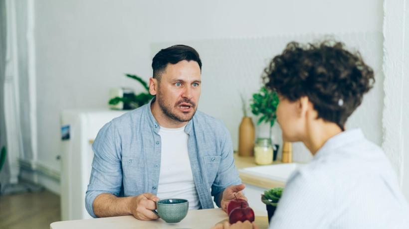Ein Mann und eine Frau sitzen Kaffee trinkend an einem Tisch einander gegenüber und scheinen der Mimik nach zu urteilen zu streiten.