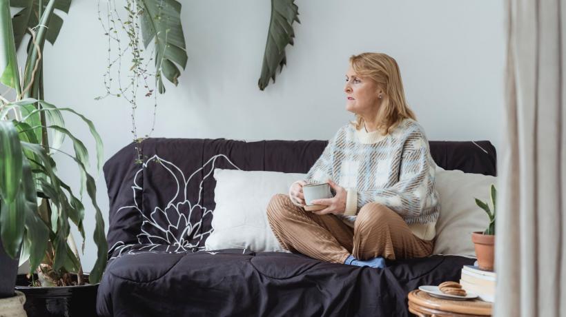 Frau sitzt nachdenklich auf einem Sofa