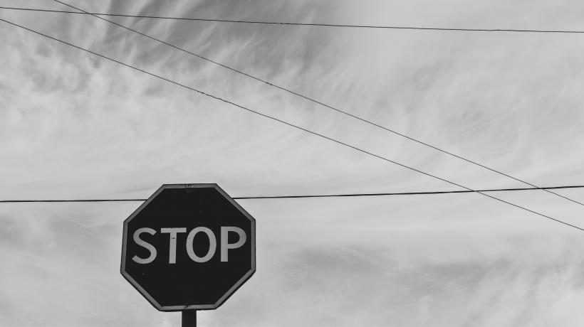 Stoppschild vor Himmel mit Oberleitungen.