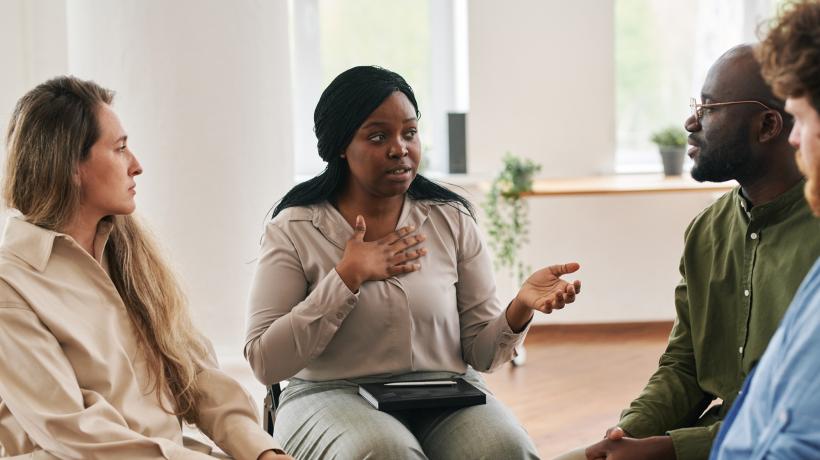 Zwei Frauen und zwei Männer unterschiedlicher Hautfarben in der Gruppentherapie.