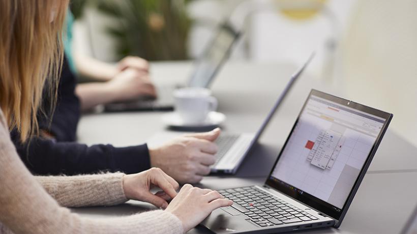 Man sieht den Ausschnitt von drei Personen, die nebeneinander am Laptop arbeiten.