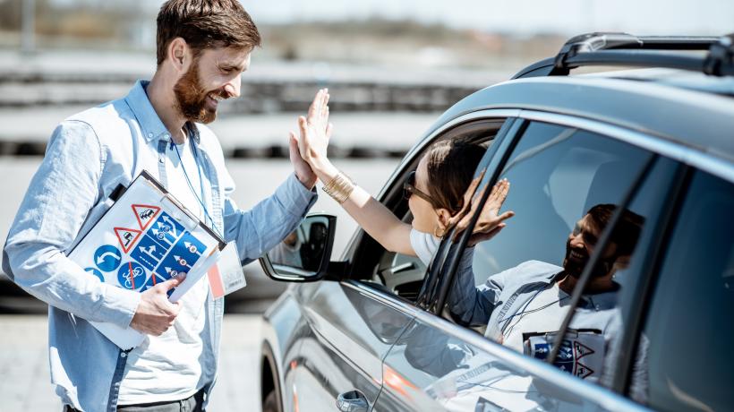 Ein Mann steht an einem Auto, dessen Fahrer ihm ein High-Five gibt