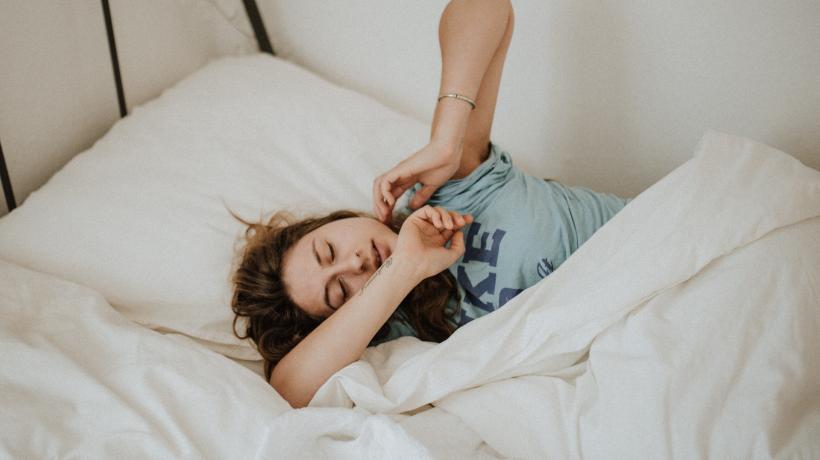 Eine Frau räkelt sich im Bett.