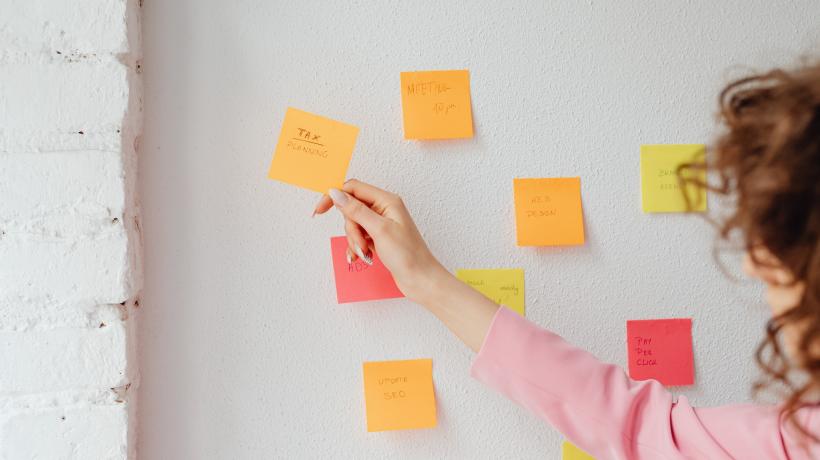 Eine Frau hängt Klebezettel mit Notizen an eine Wand.