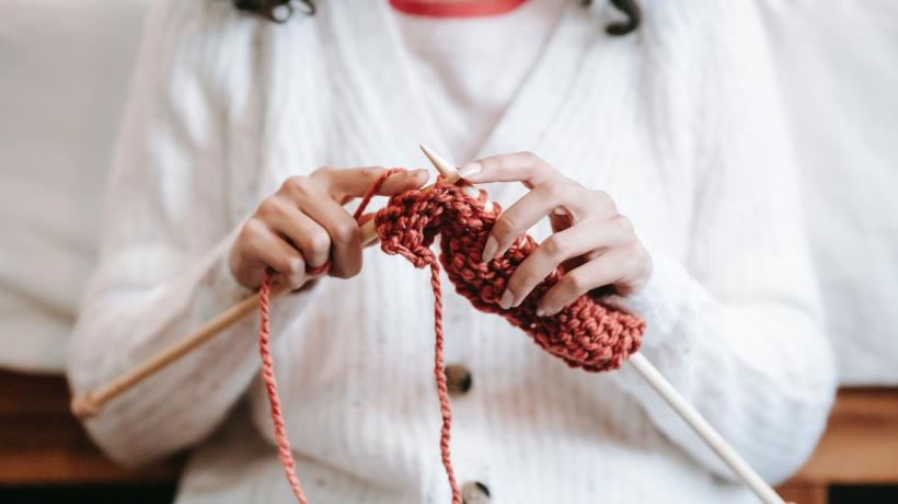 Eine Frau strickt mit roter Wolle.